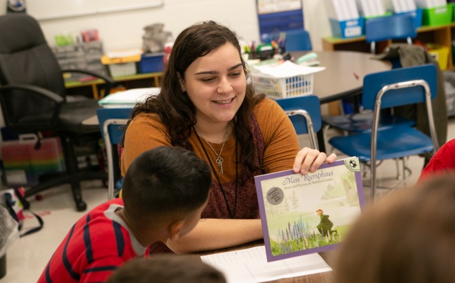 Student teacher in McKay classroom with students and book