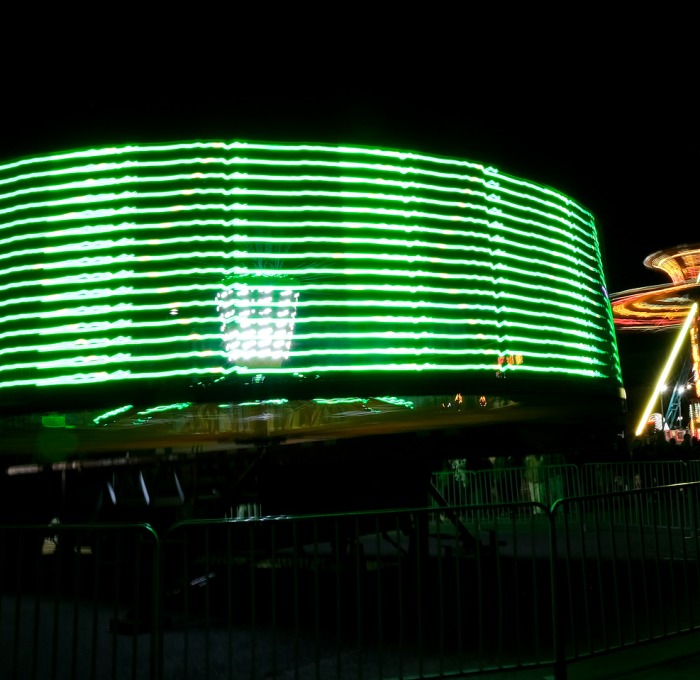 Spinning carnival rides with green and gold lights