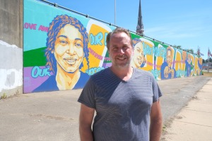 Artist John Allen in front of mural.