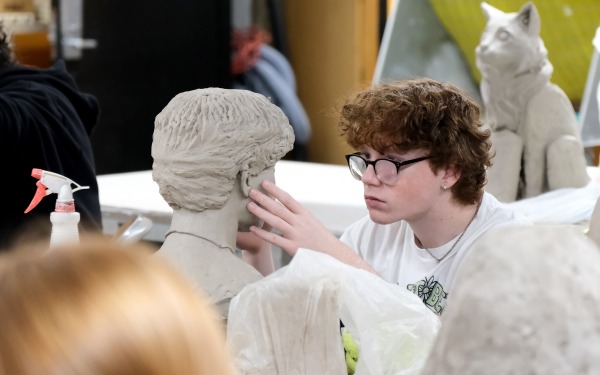 Student working on self portrait bust in Ceramics class