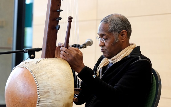 Close up of John Hughes playing the Kora a string instrument