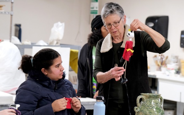 Sally Moore holding puppet and student looking on