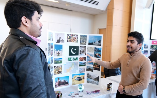Student with his presentation board on Pakistan talking to another student at study abroad fair