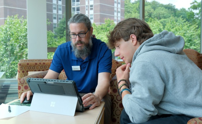 Senior associate registrar Mark LeBlanc working with male student on tablet to register for classes