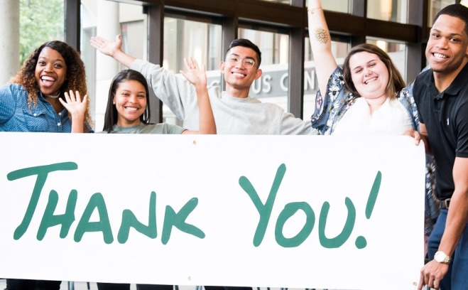 Happy students holding thank you sign