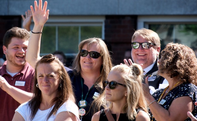 Smiling staff on the quad waving at the state of the university address