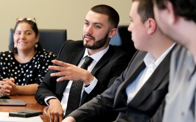 Students in suits competing in discussion at table