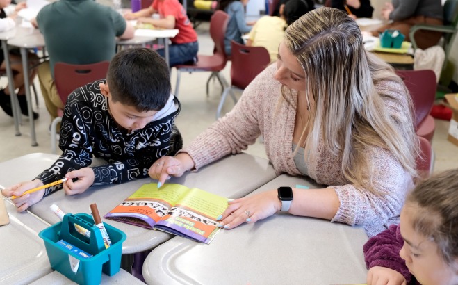 Student teacher reading with students at table