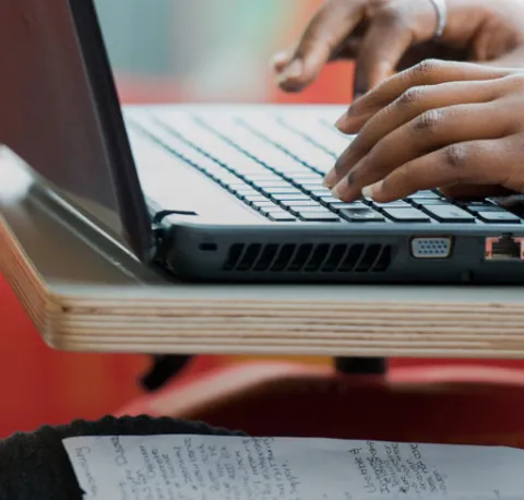 Student typing on a laptop in the library