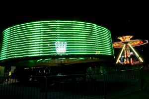 Spinning carnival rides with green and gold lights