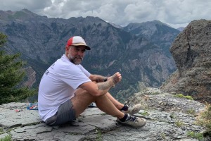 Jeff Godin sitting on the top of a mountain