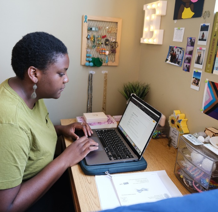 Evie in her Simonds dorm on her laptop at desk