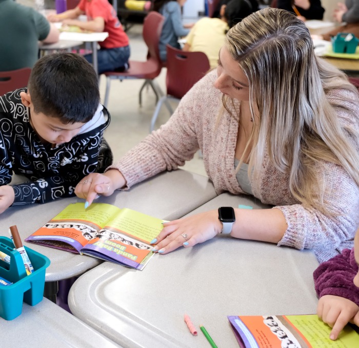 Student teacher reading with students at table