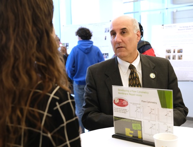 President Lapidus speaks with student at research presentation