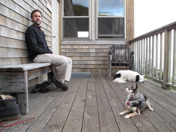 René Reeves, Ph.D. sitting on a porch with two dogs.