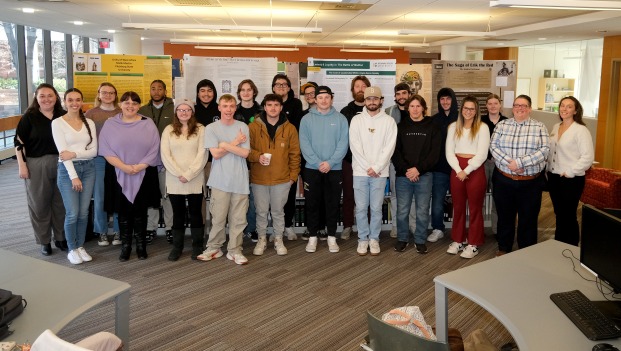 Students from Dr. Kisha Tracy's ENGL 3030 Global Middle Ages class in the Library in front of an exhibit of their research posters